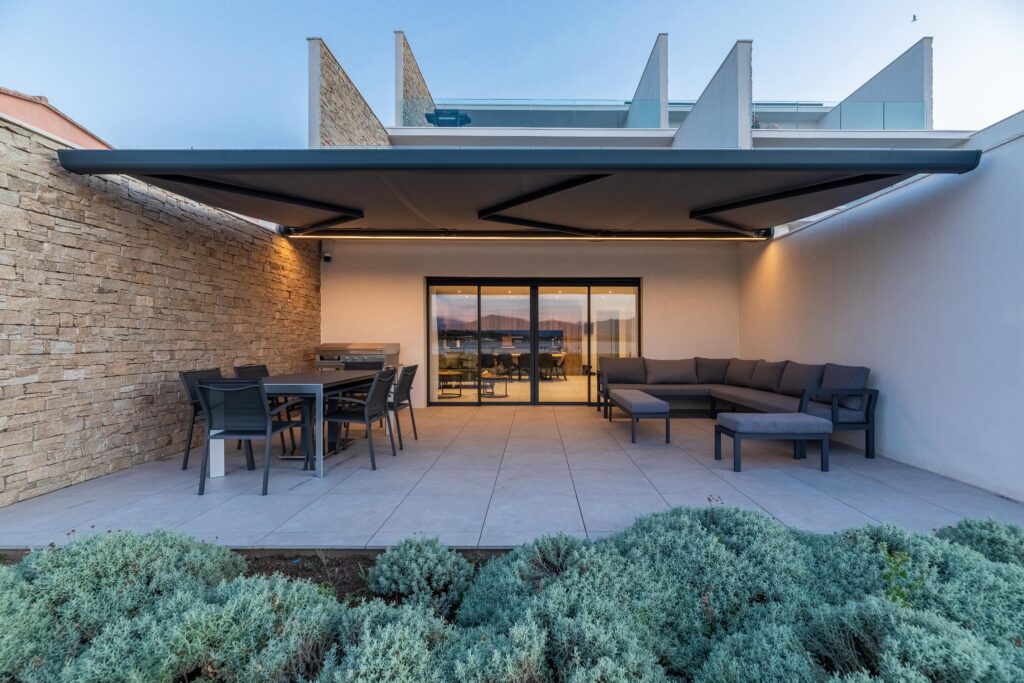 Store banne BIO KD BIOSSUN de face avec éclairage LED intégré sur une belle terrasse en Corse