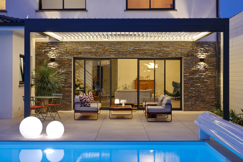 Pergola bioclimatique BIO 230 avec éclairage LED blanc Biossun installée à Mérignac devant une maison avec une piscine