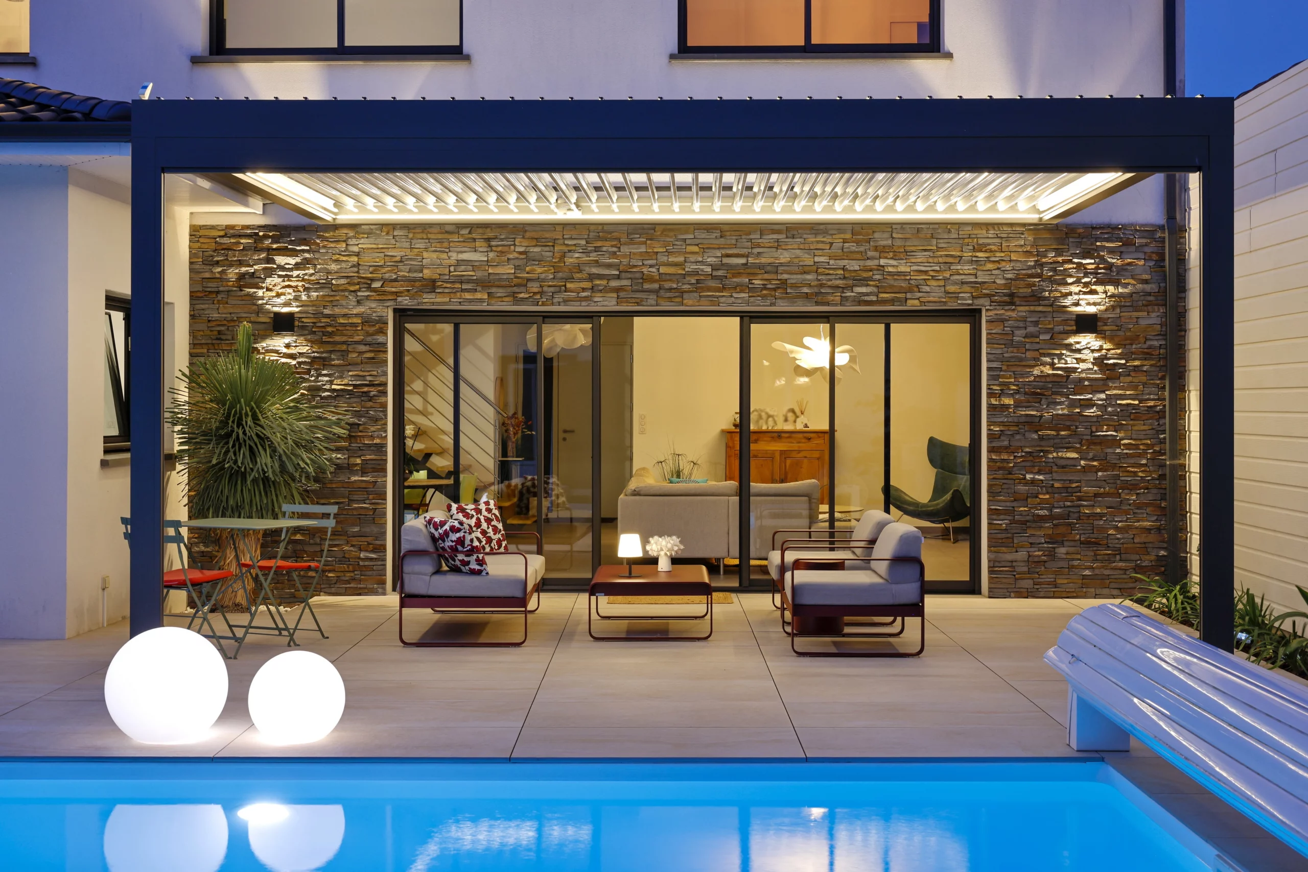 Pergola bioclimatique BIO 230 avec éclairage LED blanc Biossun installée à Mérignac devant une maison avec une piscine